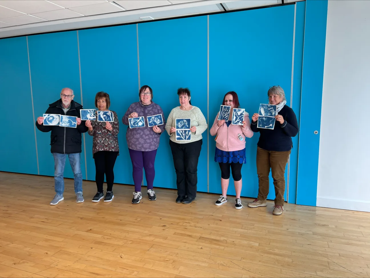 Sun-prints or cyanotypes being held up by 6 participants in the workshop
