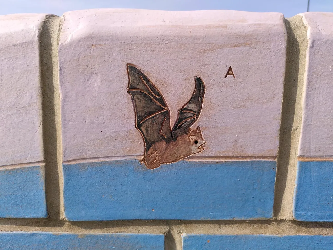 A section of a colourful sculptural bench, depicting a bat in flight